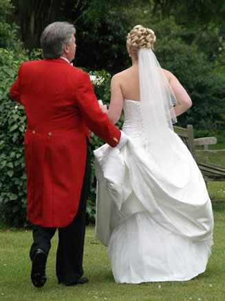 English toastmaster assisting a bride with her wedding dress